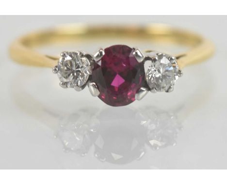 An 18ct gold ruby and diamond three stone ring, the central ruby approx 0.85ct, combined diamond weight approx 0.34ct, size N