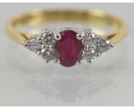 An 18ct yellow gold ruby and diamond set half hoop ring, the central oval cut ruby approx 0.4ct, flanked by two sets of three