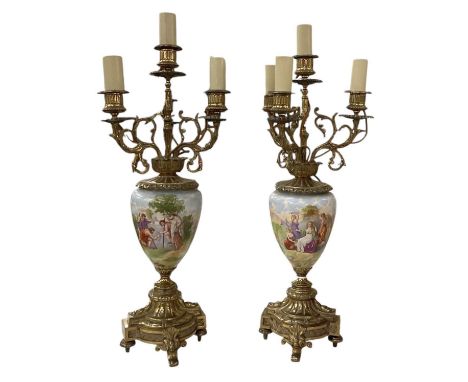 A pair of reproduction gilt metal mounted hand painted porcelain urn four branch candelabra, the porcelain urns decorated wit