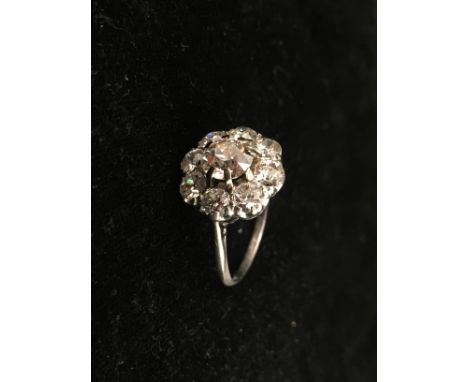 A platinum diamond daisy ring, central old brilliant cut stone: spreads 1.5ct; Moes measure 1.12ct with approx 8 0.20 pts sur