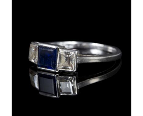 An Art Deco style sapphire and diamond three-stone ring, the central square step cut sapphire approximately 5mm wide, flanked