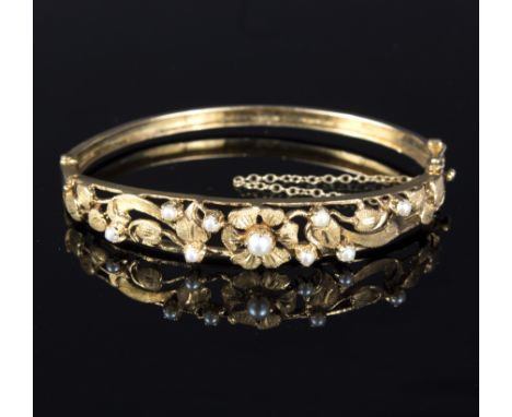 A 9ct gold bangle with pierced foliate detailing set with cultured pearls, gross weight approximately 13.5gm
