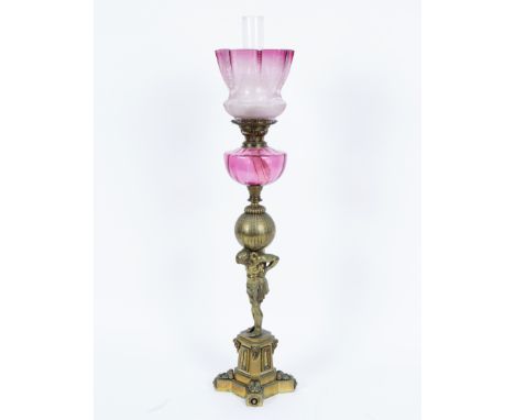 A gilt brass oil lamp, modelled as Atlas with the world on his shoulders, with pink glass reservoir and shade, 93.5cm high   