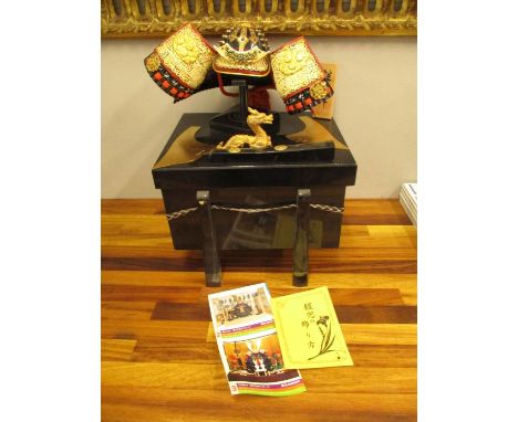A miniature reproduction model of a Japanese Kabuto helmet, contained in a black lacquered lidded box, with paperwork 