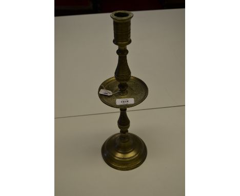 Antique brass candlestick with a cast drip tray raised on turned column support with domed circular base