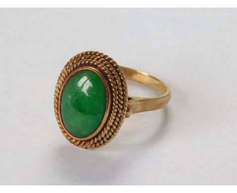 JADE RING. A 14k. ring set a leaf green jadeite stone within a rope twist border. Size L/M.  Please note that all items in th