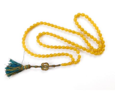 CHINESE NECKLACE. A Chinese, yellow bead necklace, possibly jadeite, hung with a gold thread tassel. Approx. length of beads,