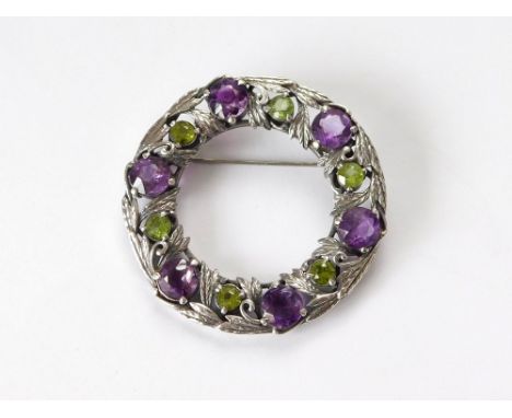 SILVER BROOCH. A silver wreath-style brooch, possible Cornish Stone Co., set with amethyst & peridot. Diameter 5.2cm.  Please