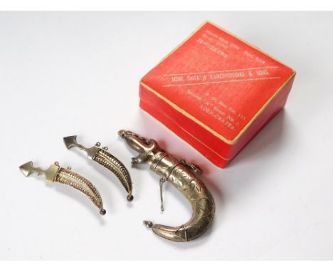 SCIMITAR BROOCHES. Three Middle Eastern scimitar brooches, in silver coloured metal, the largest approx. 7cm, in original box