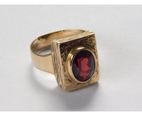 GOLD RING. A 9ct. gold dress ring set an oval garnet in a textured mount. Size O.  Please note that all items in this auction