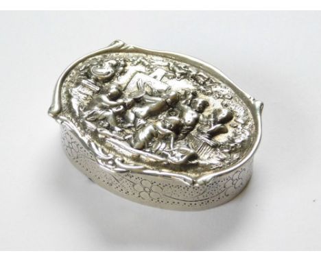 SMALL BOX. A continental (?) silver coloured metal oval box, the lid cast with putti. The interior gilded & with two stamped 