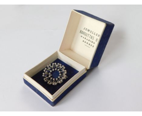 GEMSTONE BROOCH. An unmarked white metal, sapphire & diamond flowerhead brooch. Diameter 2.7cm. In a fitted Rhodes retail jew