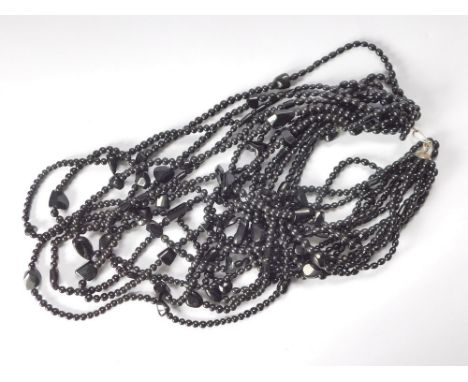 BLACK BEAD NECKLACE. A long necklace comprising fourteen strands of black composition round beads & larger random beads. Max.