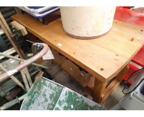 A wooden workbench complete with woodworking vice and a box of tools. 