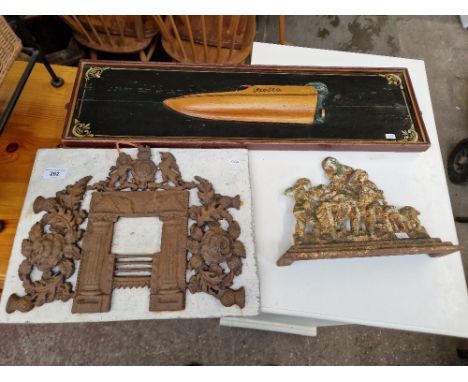 A wooden relief model of a speedboat, a metal ornament and a metal door stop. 