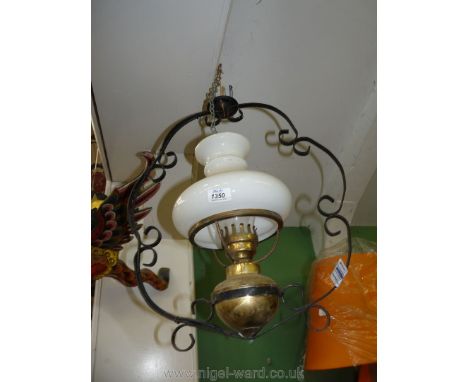 A brass oil lamp in a metal banjo style hanging frame.