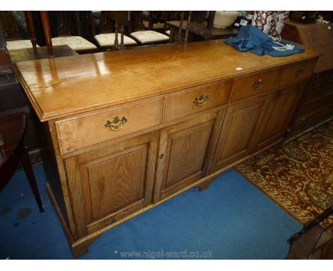 A contemporary mid oak sideboard having faux frieze drawers with pierced back plate brass drop handles and with two pairs of 