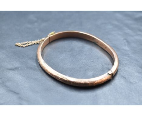 A 9ct rose gold hinged bangle having engraved decoration, approx 8.2g