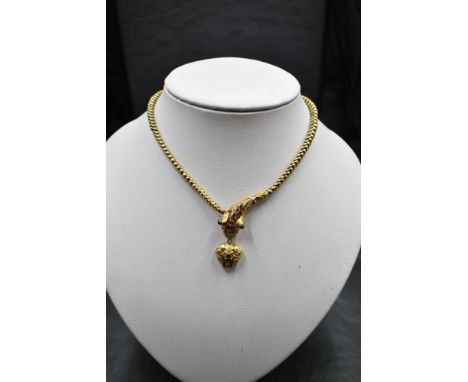 A Victorian yellow metal serpent/snake necklace having a ruby set moulded head with suspended heart shaped drop with glass lo