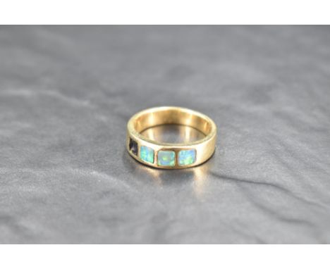 A yellow metal band ring stamped 585 having four inset black opal panels, one missing, size U &amp; approx 9g