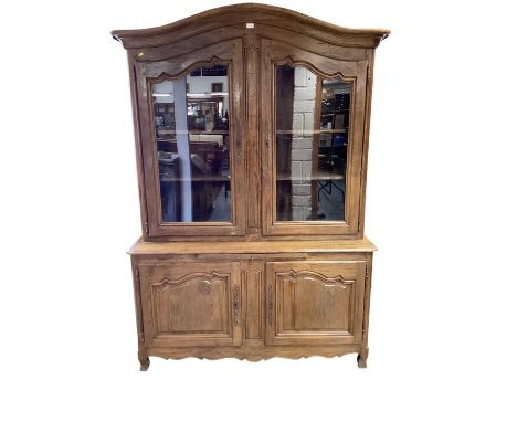 French chestnut two-height cabinet, the arched glazed top enclosing shelves, above twin panelled cupboard doors below, on sha