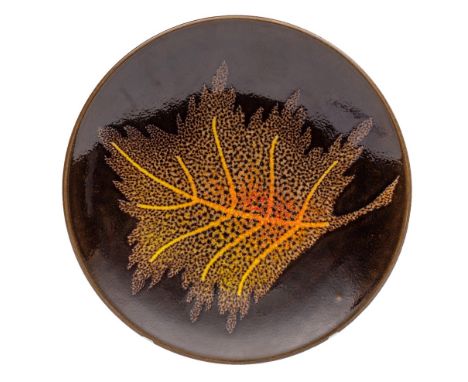 A Poole pottery Agean plate, with yellow and orange leaf decoration on a brown ground, printed mark and painted monogram for 