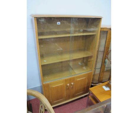 An Oak Book Cabinet, in the Ercol manner, having sliding glass upper doors over solid cupboard doors, 82cm wide.