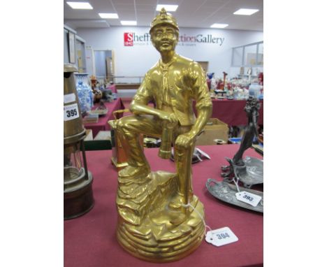 A Brass Figure of a Coal Miner, leaning on a pick axe, holding a lamp, 31cm high.