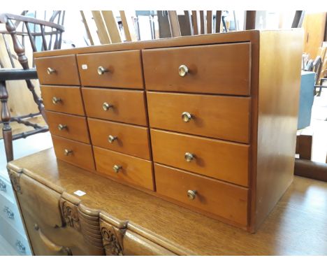 A LIGHT WOOD UTILITARIAN TABLE CHEST OF DRAWERS