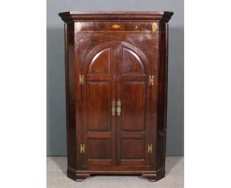 A late Georgian mahogany corner cupboard with moulded cornice, the frieze carved with oval shell motifs, fitted three shaped 