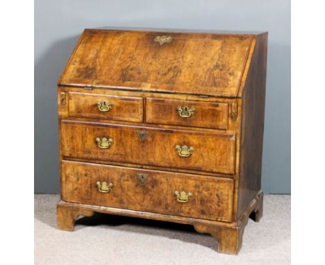 A George II walnut bureau, the top slope and drawer fronts inlaid with stringings and crossbanded, the slope enclosing centra
