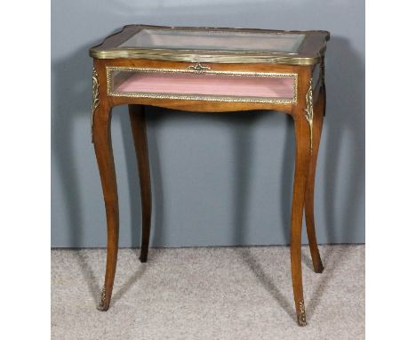 A 20th Century French stained wood and gilt brass mounted rectangular display table, the lifting top of serpentine outline an