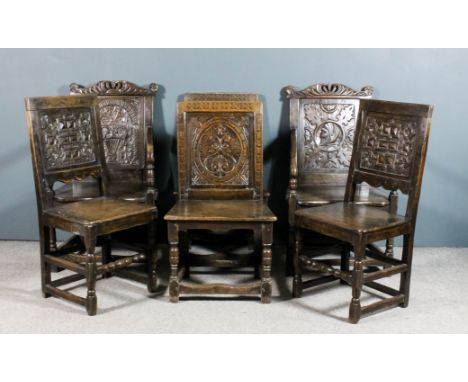 A pair of old panelled oak dining armchairs of "17th Century" design, the shaped crest rails pierced and carved with crown an