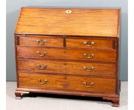 A George III mahogany bureau, the slope enclosing fitted interior with central cupboard, pigeon holes and ten small drawers, 
