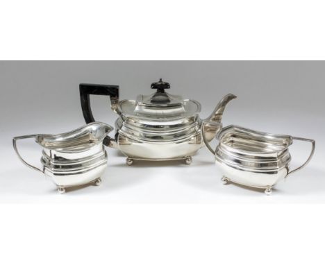 A George V silver rectangular three piece tea service with gadroon mounts and moulded bodies, angular loop handles and on fou