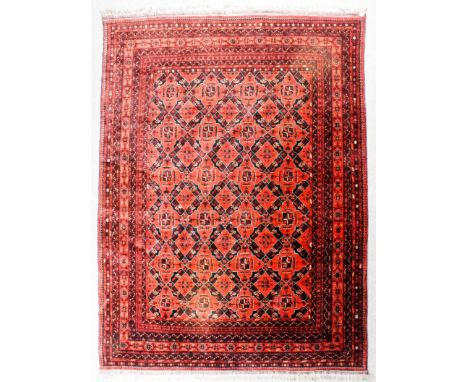 A Turkmen carpet woven in navy blue, rose, fawn and ivory with trellis design of lozenge motifs, filled with cross motifs, on