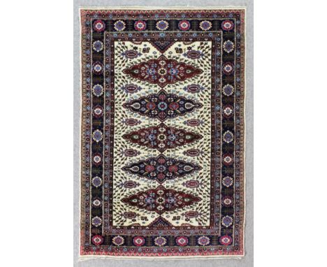 An Indian rug of "Persian" pattern woven in colours with five floral filled ovoid medallions, field filled with stylised leaf