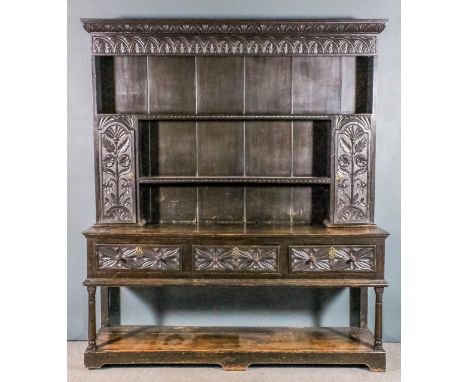 A 19th Century dark oak dresser carved with leaf ornament and flowerheads, the upper part with moulded cornice, fitted two sh