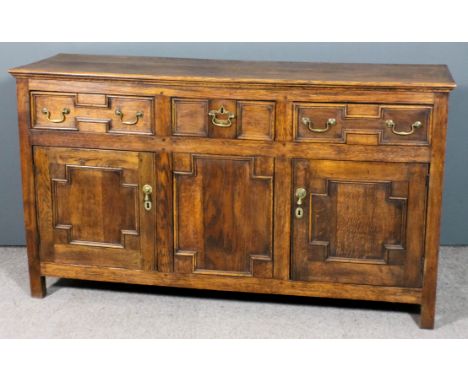 An early 19th Century panelled oak dresser base with plain top, fitted three frieze drawers with twin moulded and raised pane