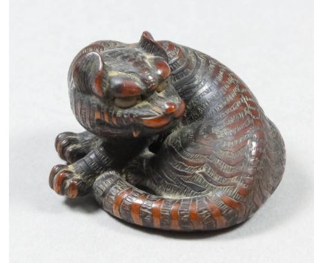 A Japanese carved hardwood Netsuke of a tiger, 1.5ins (3.8cm) x 1ins (2.55cm) high, signed