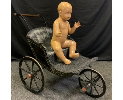 A Victorian style  invalid carriage, black painted three wheeled body, push handle, with baby doll shop mannequin 