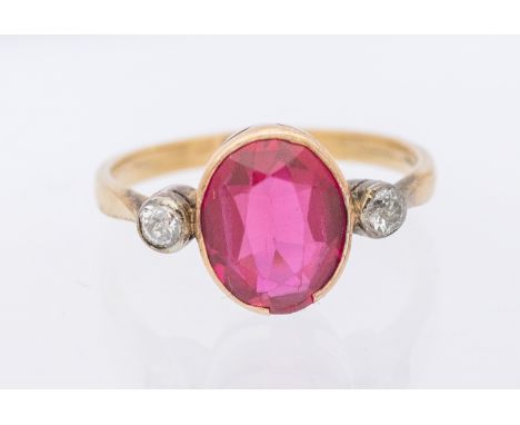 A synthetic ruby and diamond three stone 9ct gold ring, set with an oval ruby approx 9x7mm, single diamonds set to each shoul