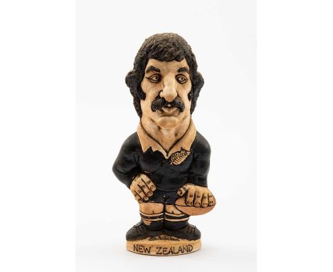 GROGG CARICATURE BY JOHN HUGHES OF GRAHAM MOURIE standing on titled base, wearing his All Blacks No.7 kit, holding the ball i