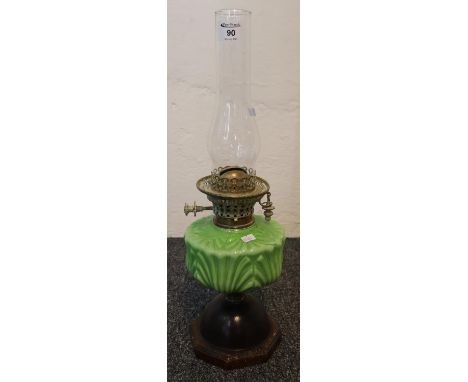 Early 20th Century double burner oil lamp having glass chimney with green ceramic reservoir on a bulbous metal hexagonal base