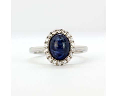 An 18ct white gold ring set with a cabochon cut sapphire and brilliant cut diamonds, (N).