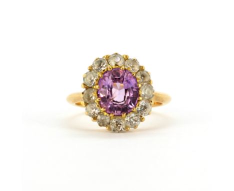 A yellow metal (tested high carat gold, approx. 22ct) cluster ring set with a large oval cut pink sapphire surrounded by whit