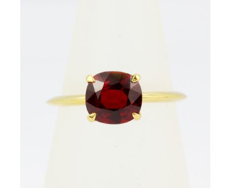 A yellow metal (tested high carat gold) solitaire ring set with a cushion cut Burmese pigeon blood ruby, (M).