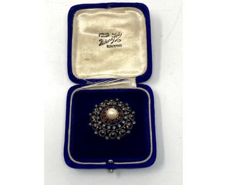 A vintage circular brooch set with diamonds pearls and garnet, stamped 18ct.