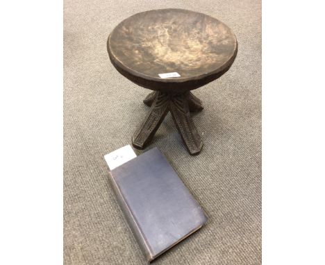 A Nigerian Niger Ibos carved wooden chieftain stool, with carved underside to the circular seat above a carved four-way suppo