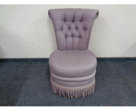 An upholstered bedroom chair with button back. 
